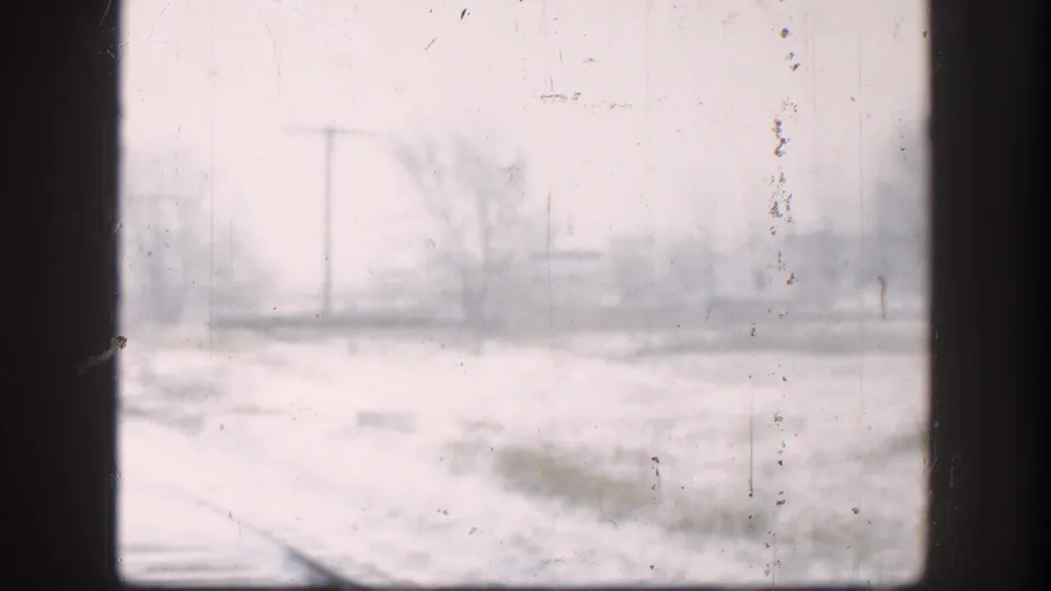 Kansas 1958 home-movie still of a snowy rail-side landscape with bare trees, utility poles, and visible 8mm wear.
