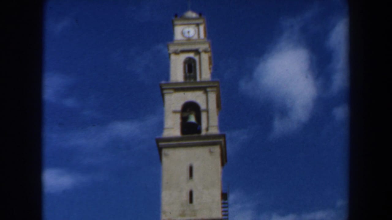 Church steeple centered beside a white cloud in a blue sky.