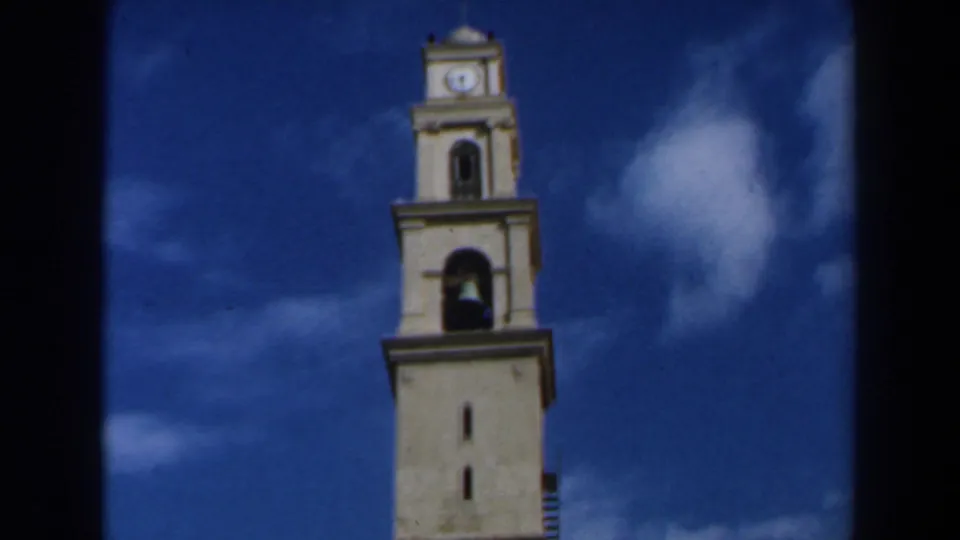 The tower remains framed high against the sky, with its arched bell opening and clock face visible near the top.