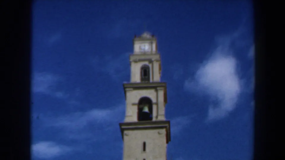 The final frame keeps the tower top and clock face visible against a blue sky, with 8mm grain and contact-sheet borders.