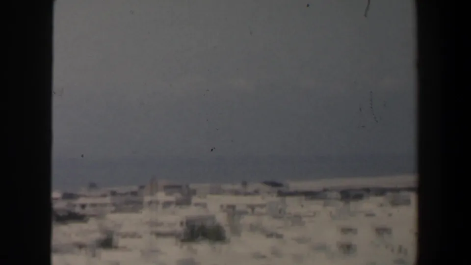 1960 Israel elevated view across pale rooftops toward a soft blue-gray shoreline and sky.