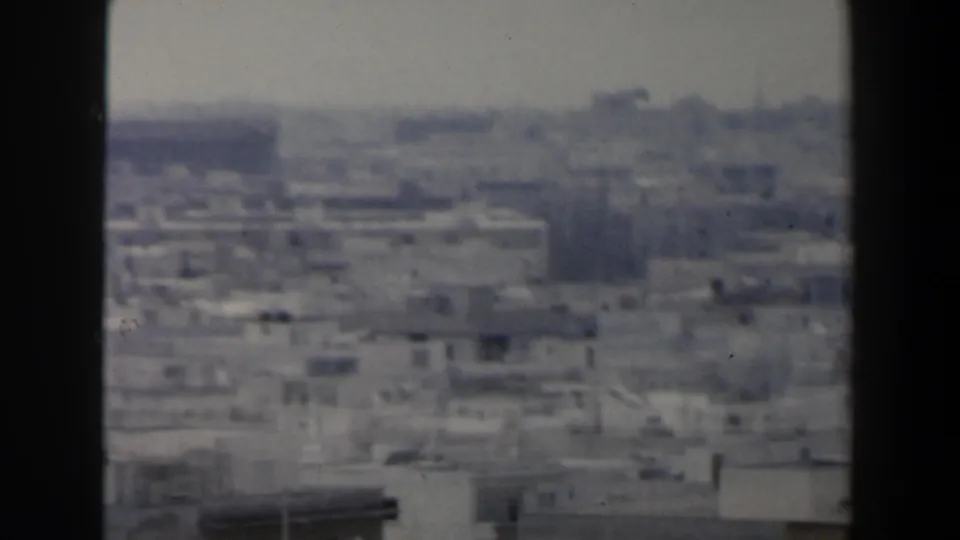 1960 Israel frame showing a soft, hazy sweep across tightly packed low buildings and sparse tree shapes in the distance.