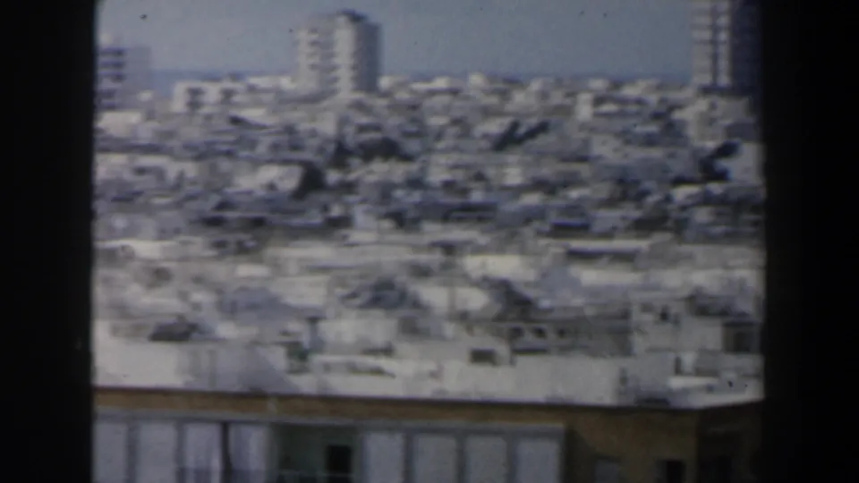 1960 Israel home-movie view over a crowded urban skyline with pale buildings and distant high-rises.