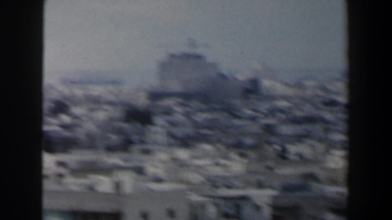 1960s Israel 8mm frame showing a hazy elevated view across dense low-rise city buildings.
