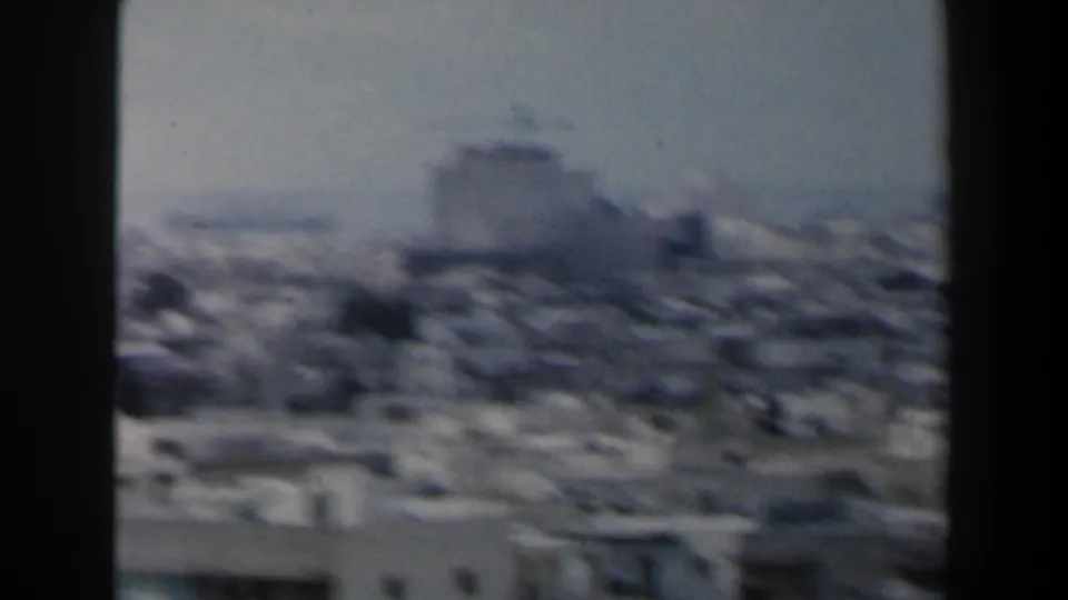1960s Israel 8mm frame showing a hazy elevated view across dense low-rise city buildings.
