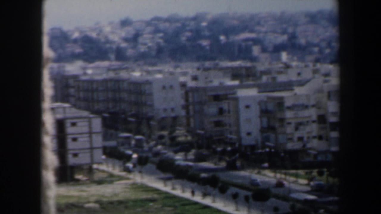 Elevated view of apartment buildings beside a road with cars and grassy strips.