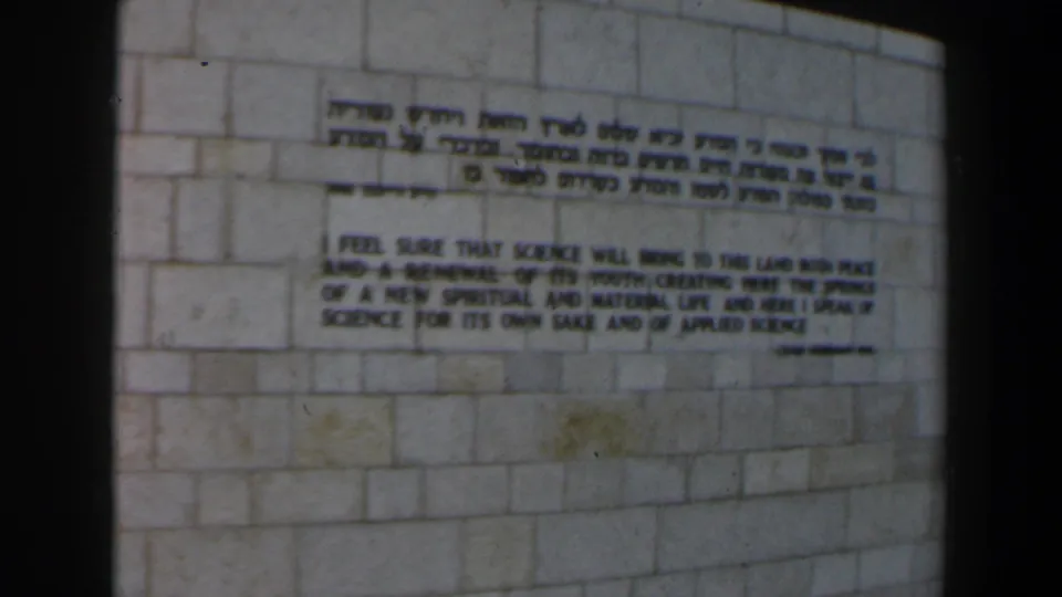 1960 Israel visitor-shot frame of a bilingual wall inscription, with Hebrew text above an English science quotation.
