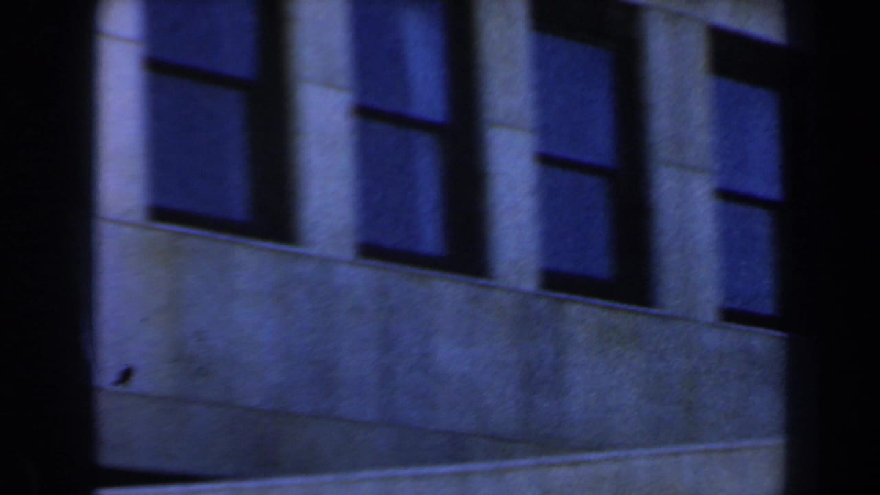 1960 Israel 8mm frame showing a modern concrete building facade with shadowed rectangular windows and heavy vertical divisions.