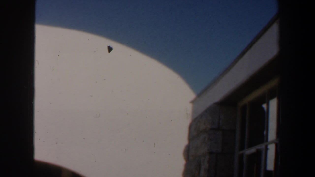 Curved white wall beside a stone section and dark-framed window.