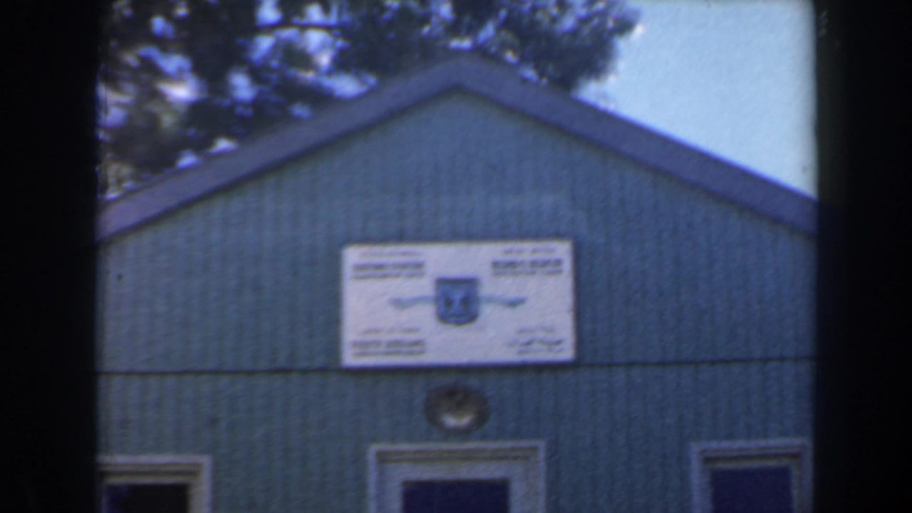 Similar view of the signed green building, framed by dark film borders.