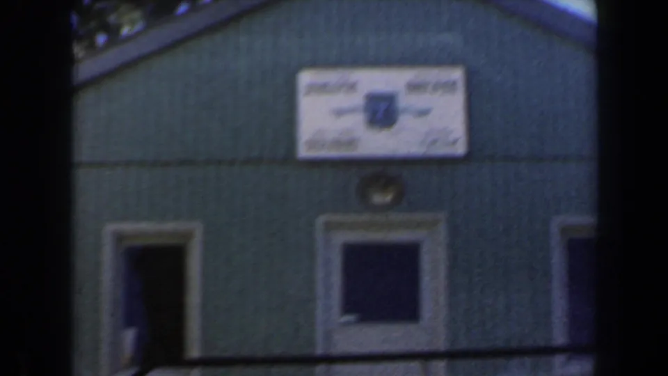 Closer 1960 Israel 8mm view of the green-sided building, with the white sign and blue emblem above the entrance.