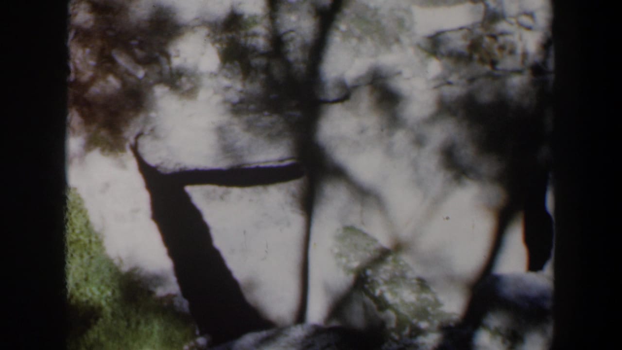 Snowy rocky ground seen through dark vertical window or doorway framing.