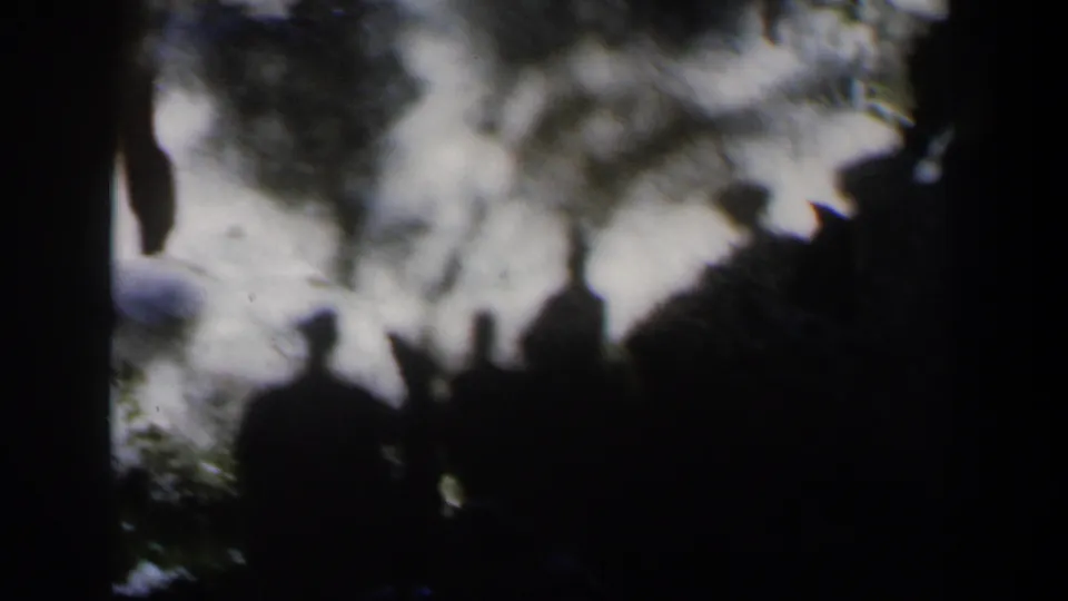1960 Israel home-movie frame with dark foreground silhouettes, snowy terrain, and soft tree shapes in the background.