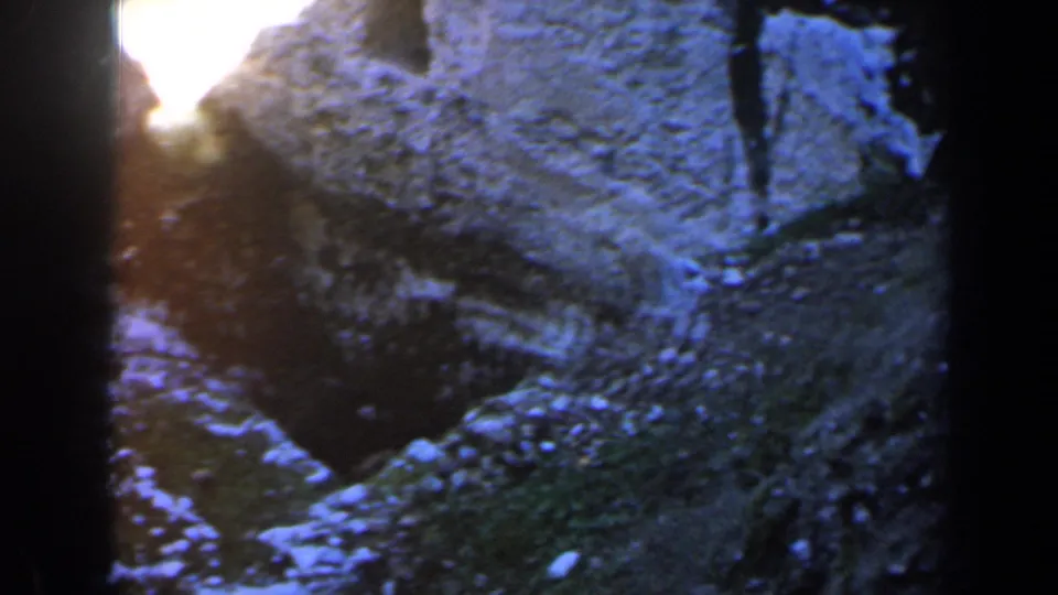 Close 8mm view of blue-toned rock or packed snow in Israel, 1960, with bright light near the dark framing.
