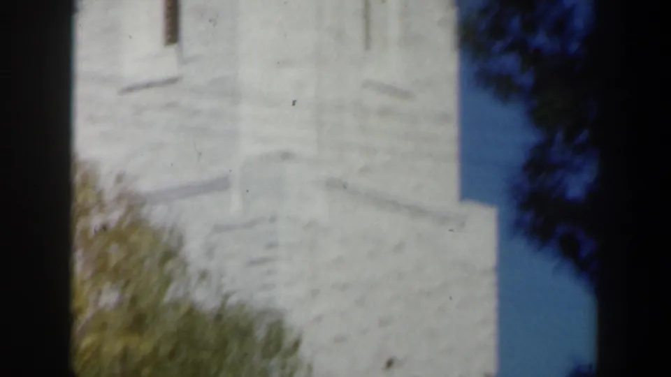 Pale stone church tower detail in Israel, filmed in soft 1960s 8mm color with blue sky at the edge.