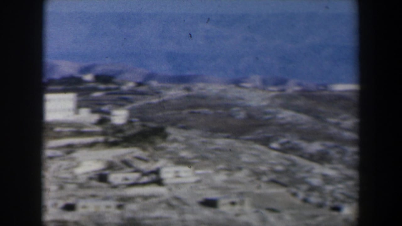 1960 Israel frame with white buildings on dry terrain, partially obscured by a dark vertical film edge.