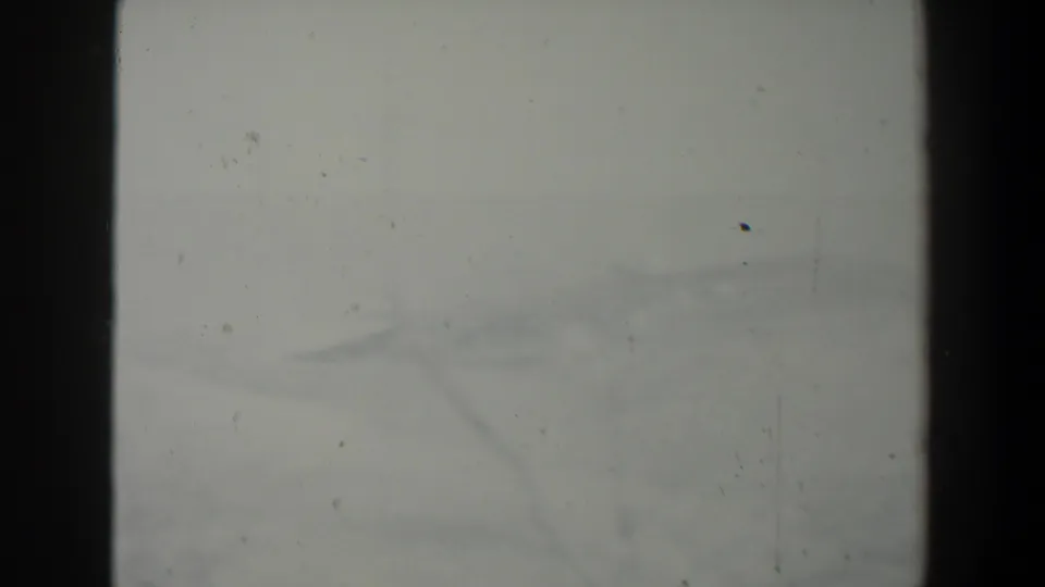 Faint end-leader frame from the 8mm scan, showing pale film, dust, scratches, and a central dark strip.