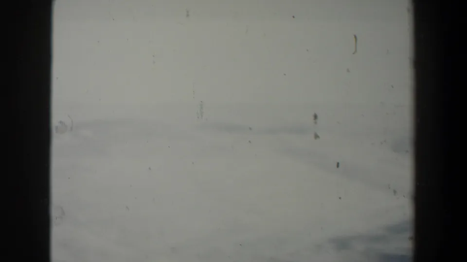 1960 Israel 8mm frame showing a pale, hazy landscape through a dark window-like divider, with visible dust and soft focus.