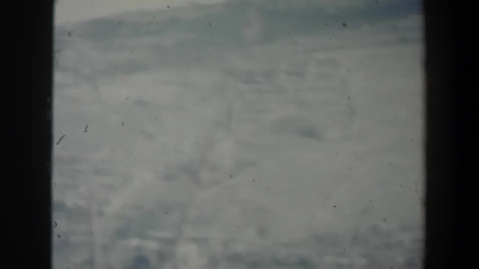 1960 Israel 8mm view of a hazy gray landscape with faint hills, film dust, scratches, and a dark divider at left.