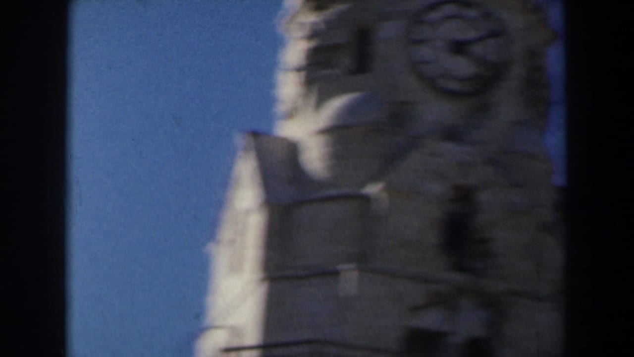 1960 Israel 8mm frame showing the upper portion of a stone structure with carved details silhouetted against blue sky.