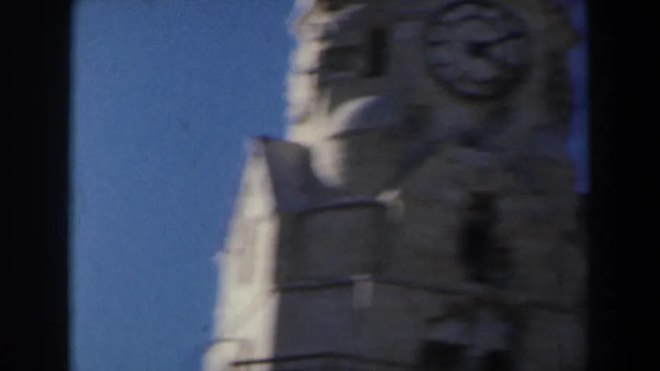 1960 Israel 8mm frame showing the upper portion of a stone structure with carved details silhouetted against blue sky.