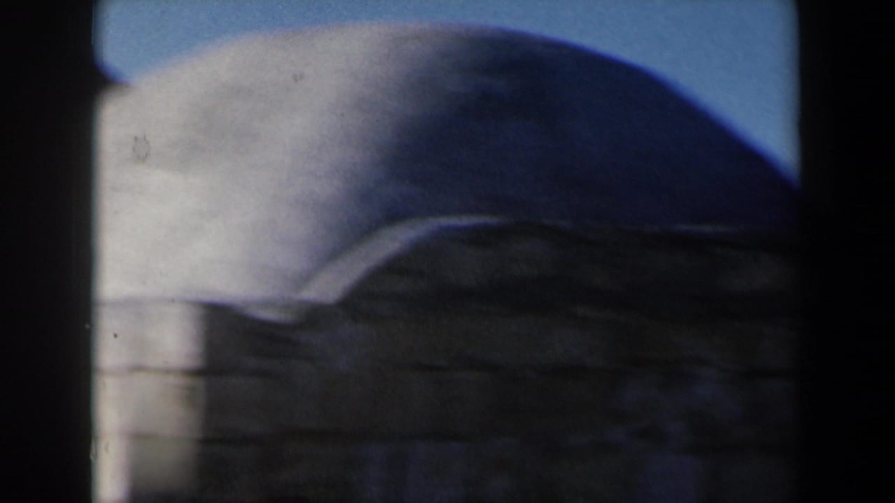Close view of a pale stone dome above darker masonry under blue sky.