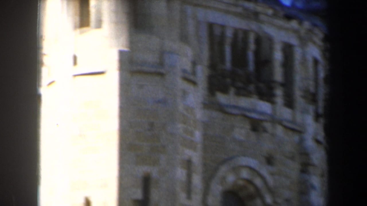 Tall pale stone tower section with arched opening and dark vertical obstruction.