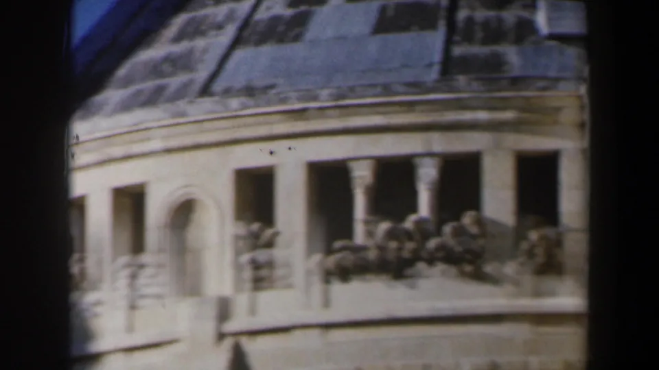 1960 Israel 8mm frame showing a curved stone facade with dark windows, a decorative ledge, and roofline details.