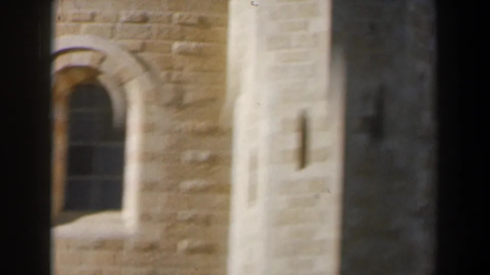 Soft 8mm close-up from Israel in the 1960s showing a stone wall, arched window, and pale vertical architectural detail.