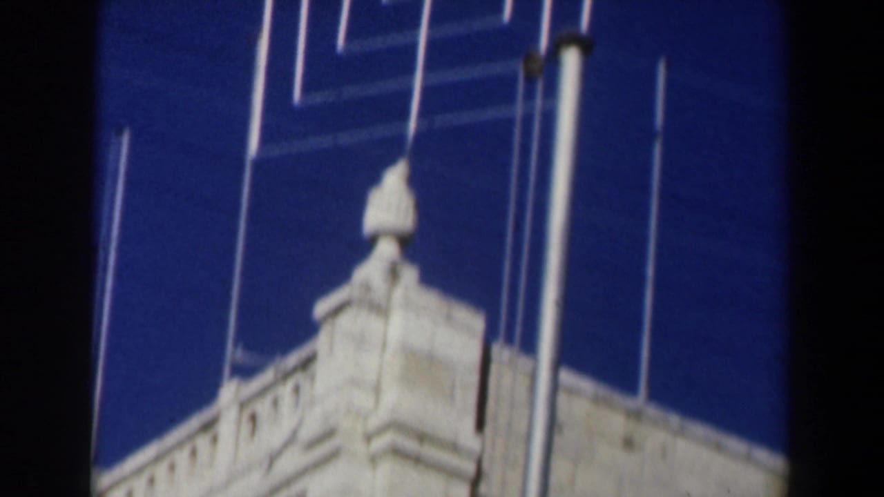 Low-angle view of a white stone roofline with vertical metal poles against a deep blue sky.