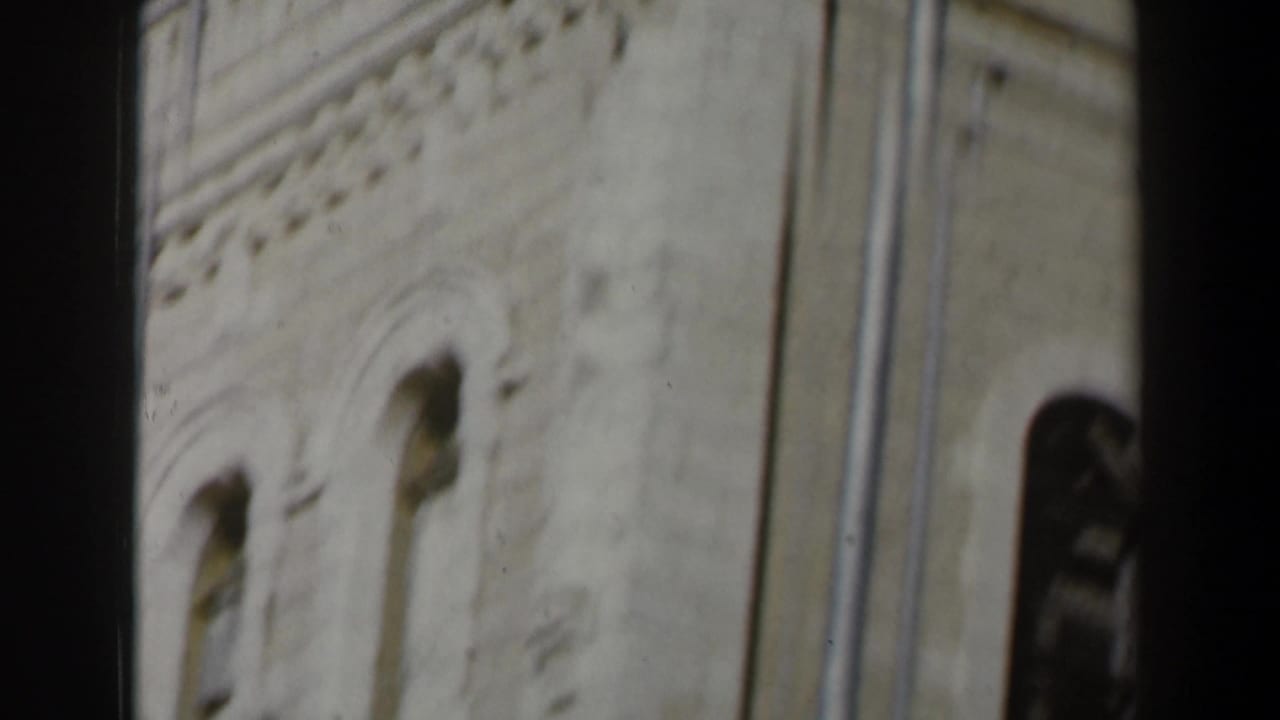 Close view of a pale stone wall with arched window openings and edge of the building.
