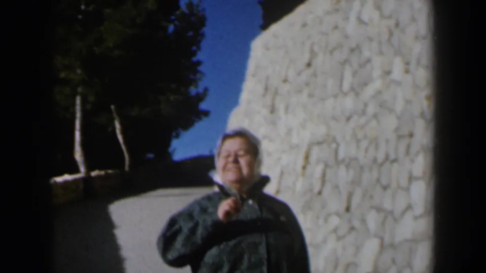 The woman fills more of the frame, smiling in bright outdoor light as she holds the front of her coat on the Israel path.