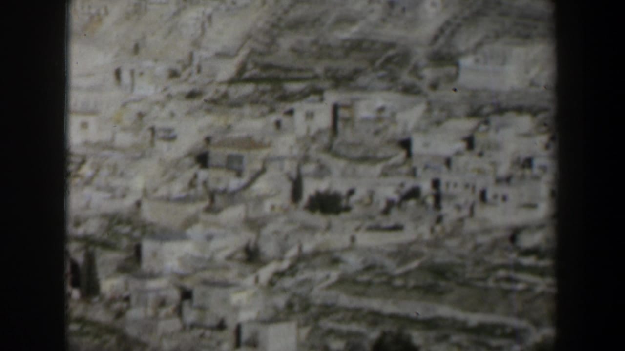 1960 Israel 8mm frame showing a dense hillside settlement of pale stone buildings in soft focus.