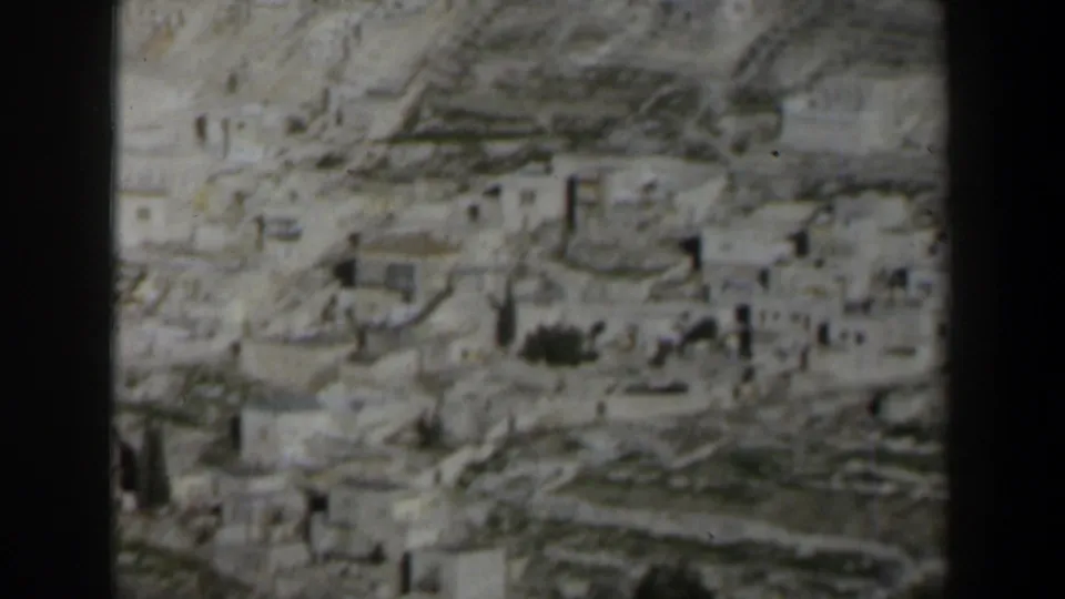 1960 Israel 8mm frame showing a dense hillside settlement of pale stone buildings in soft focus.