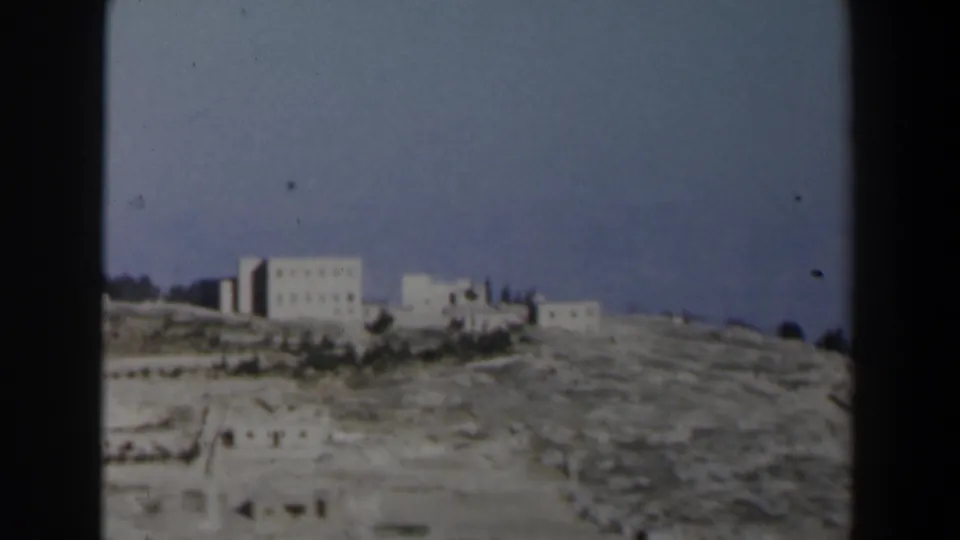1960 Israel 8mm closing frame with a large white building complex on rocky ground against a blue sky.