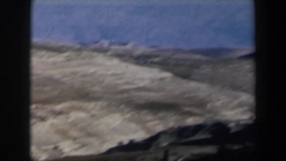 1960 Israel 8mm view of sunlit arid mountain ridges, with dark foreground bars interrupting the landscape.