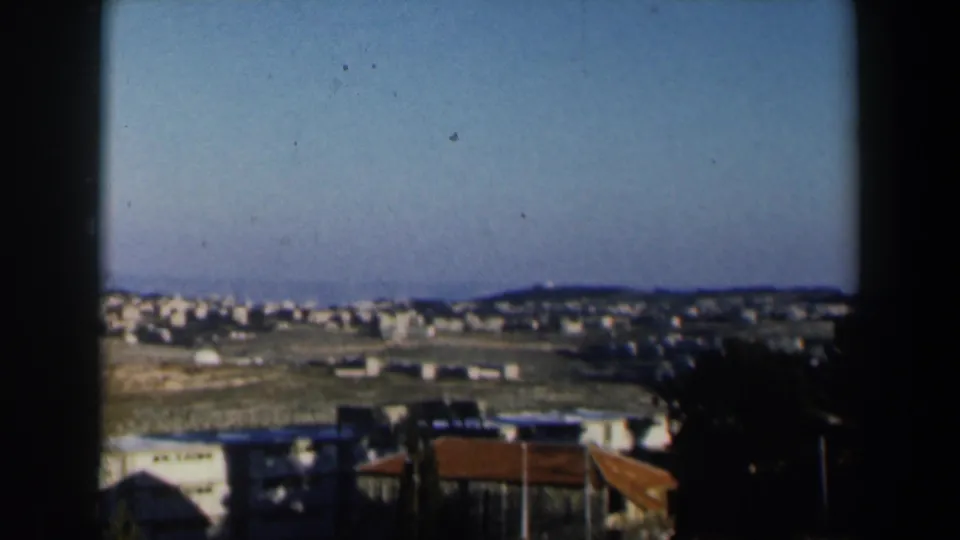 A wide view across white buildings and low hills, seen from a balcony in 1960 Israel home-movie footage.