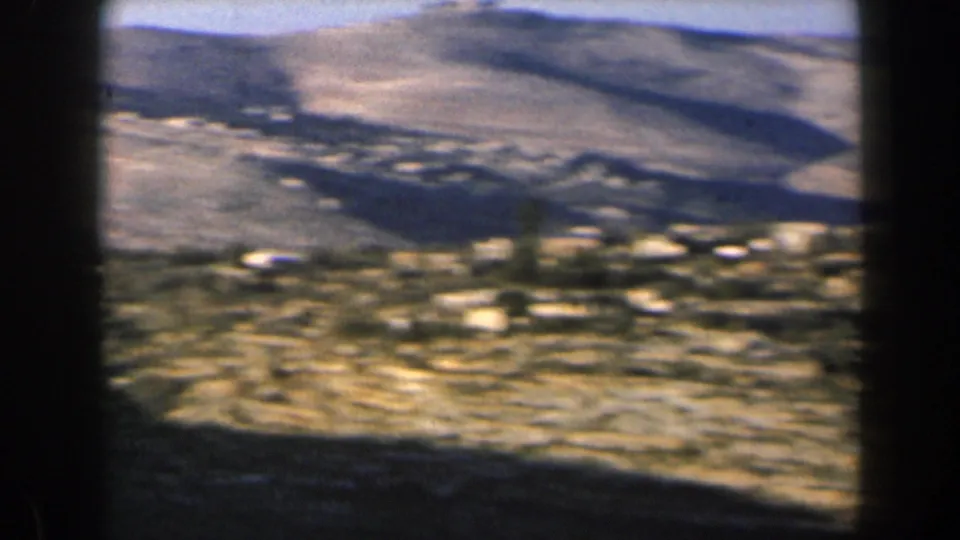 1960 Israel hill-country view with scattered buildings, pale rocky ground, and sunlit slopes in soft color.