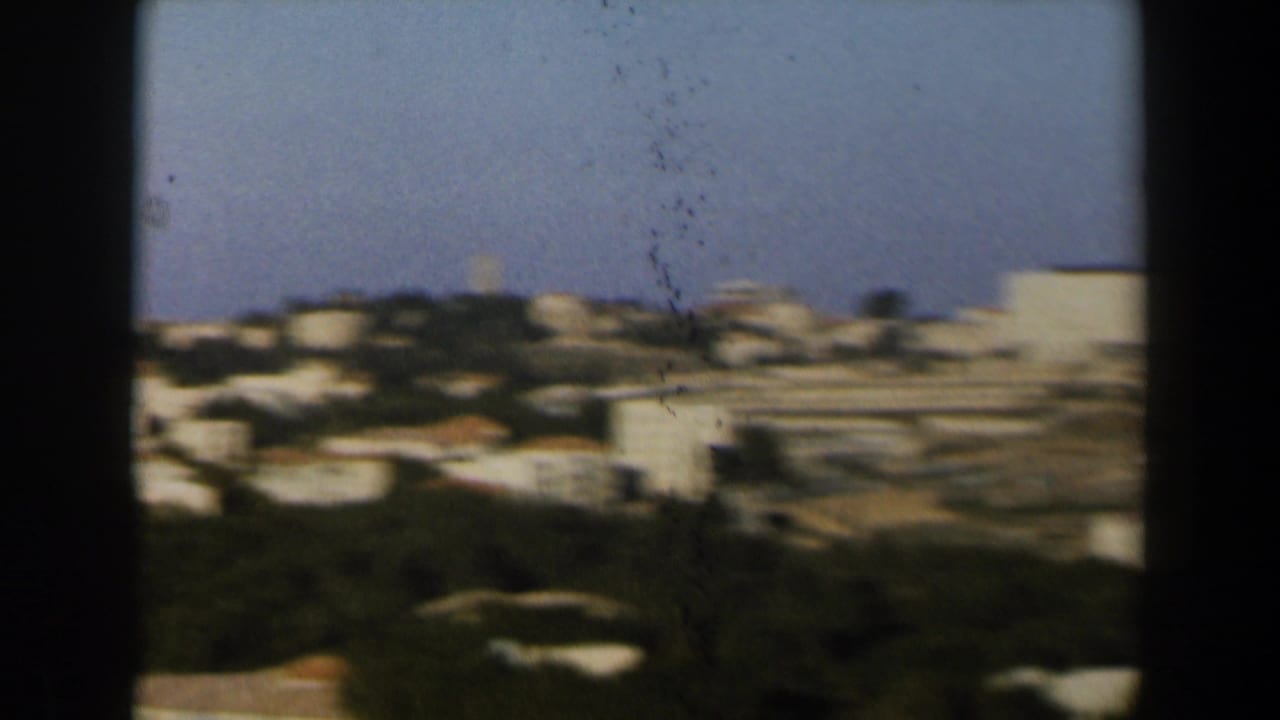 Soft 8mm view of white hillside buildings and open terrain in Israel, with the camera panning across the town.