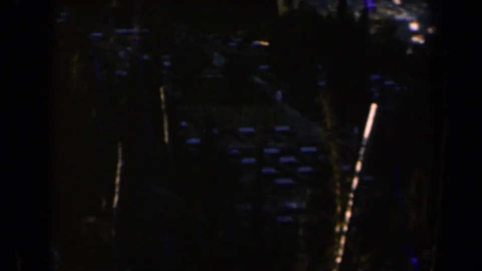 1960 Israel 8mm frame showing a dark tree-lined road or path with small lights in the distance.