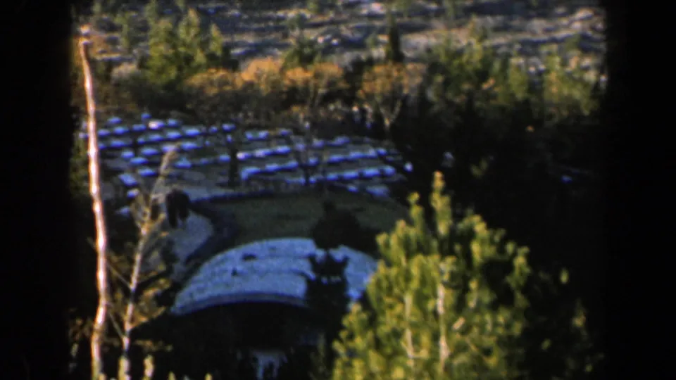 1960 Israel 8mm frame showing blue-tiled park structures among trees with a curved path and heavy film-frame borders.
