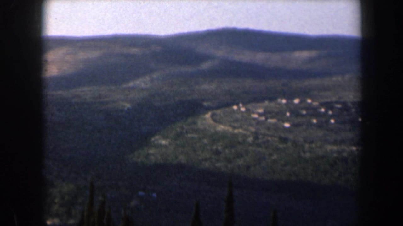 Rolling hills with a small settlement visible in the valley below.