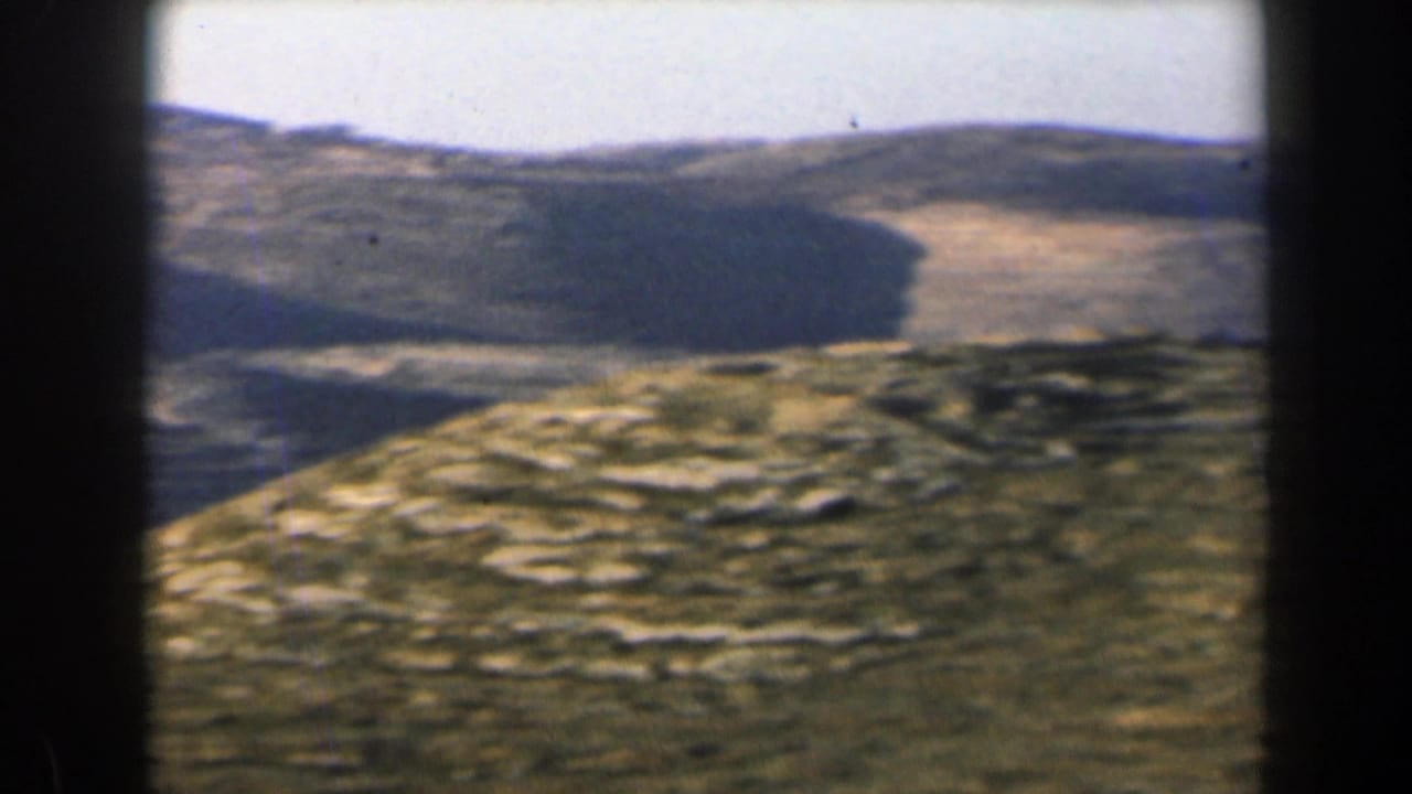 1960 Israel mountain landscape with rough rocky ground in the foreground and darker ridges across the valley.