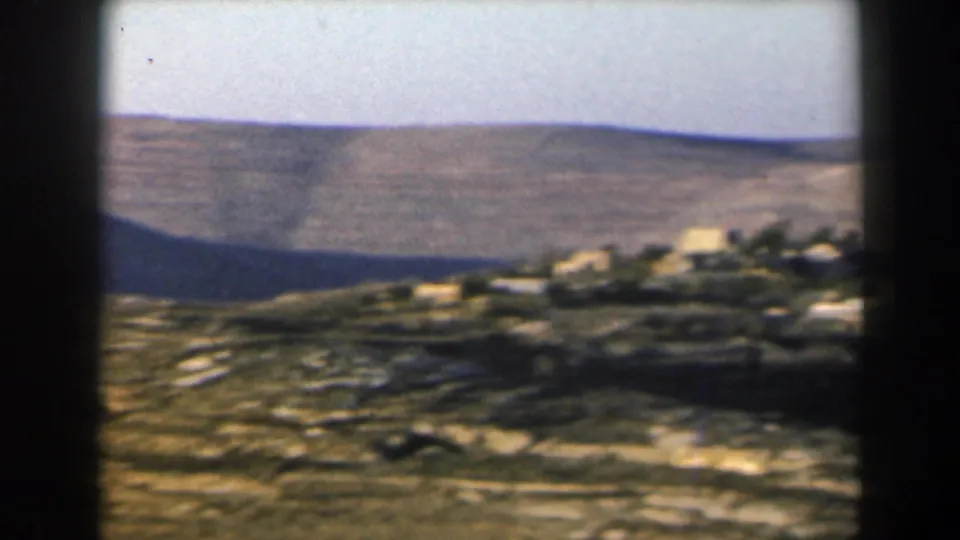 1960 Israel 8mm view of low white buildings clustered along a slope below broad arid hills.