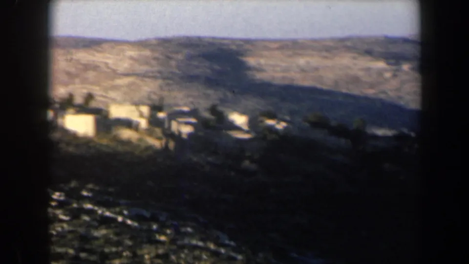 1960 Israel mountain-village view showing bright buildings against rugged hills and shadowed terrain.