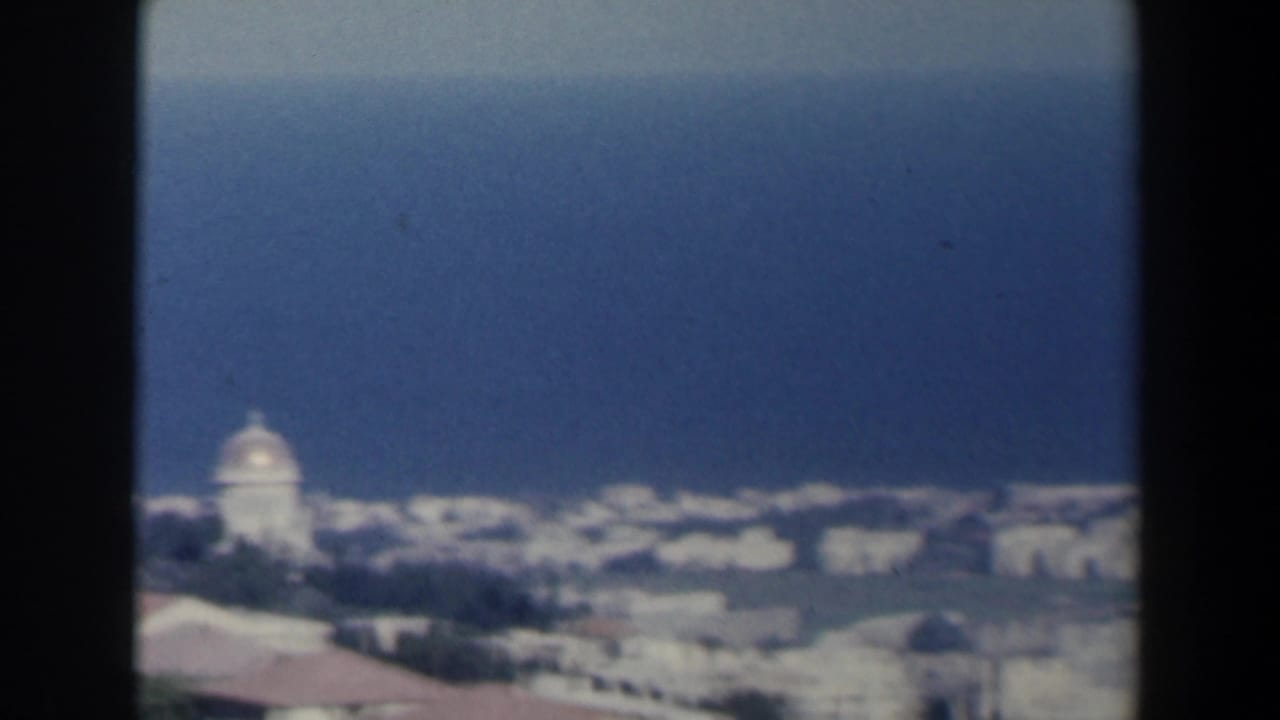 Distant coastal city skyline with a domed structure near the sea.