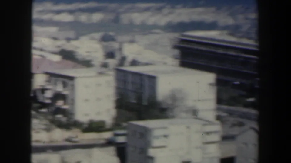 The pan passes over a dense Israeli coastal hillside, showing pale buildings, rooftops, roads, and a darker modern-looking structure.