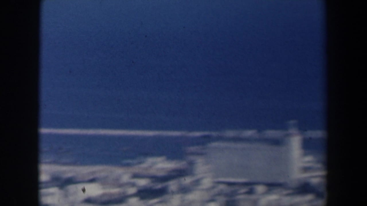 1960 Israel 8mm frame showing a soft, elevated view of port buildings beside a deep blue harbor.