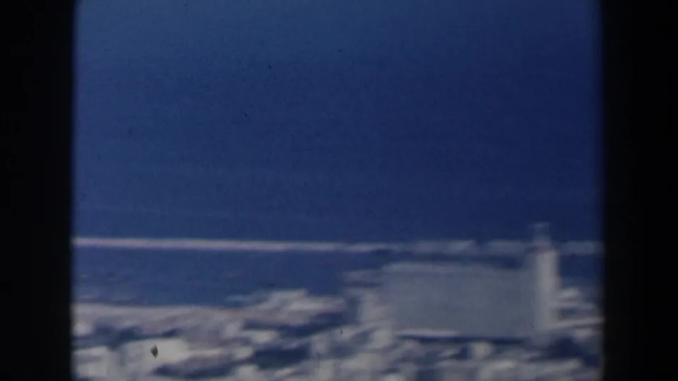 1960 Israel 8mm frame showing a soft, elevated view of port buildings beside a deep blue harbor.
