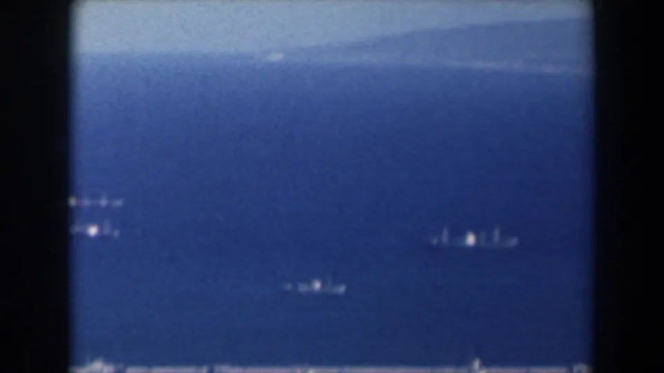 1960 Israel 8mm frame showing open harbor water, distant boats, and a hazy coastal horizon.